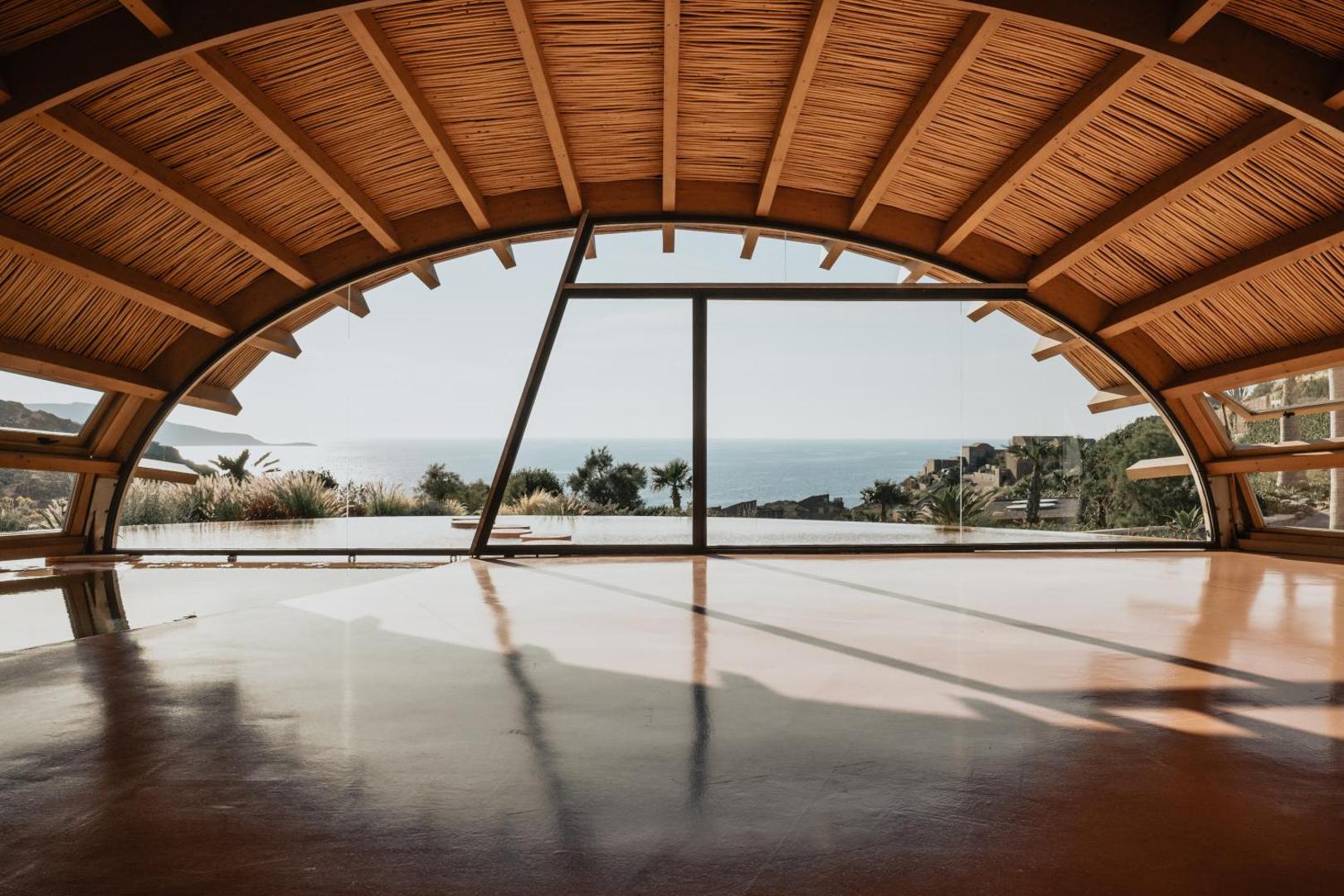 Seaside A Lifestyle Resort jogas un fitnesa zāle ar koka apdari un lielu logu, no kura paveras skats uz jūru