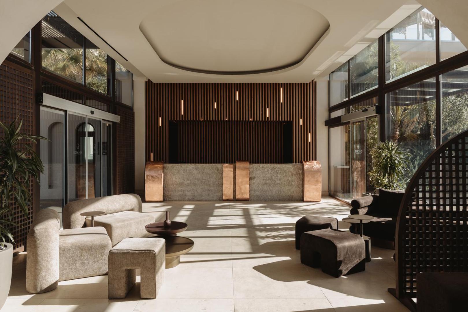 Seaside A Lifestyle Resort modernā viesnīcas recepcija un vestibils ar dizaina mēbelēm, vara akcentiem un plašiem panorāmas logiem