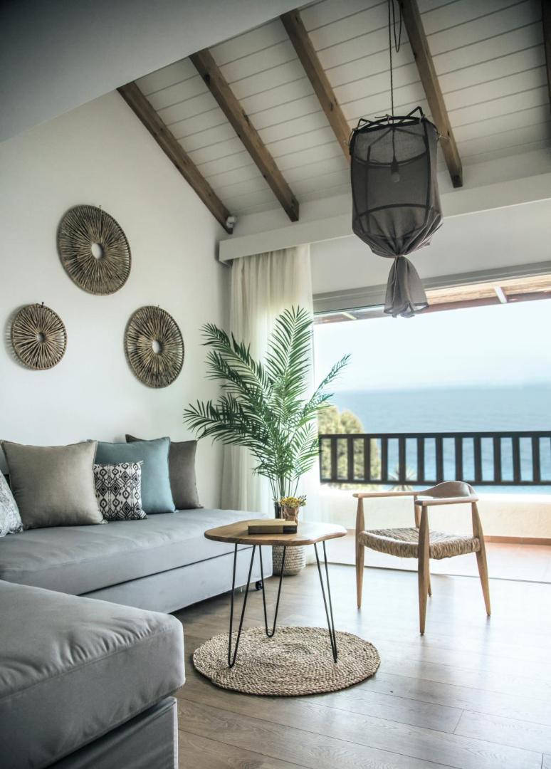 Seaside A Lifestyle Resort viesistabas zona ar pelēku dīvānu, koka galdiņu un balkonu, no kura paveras skats uz jūru