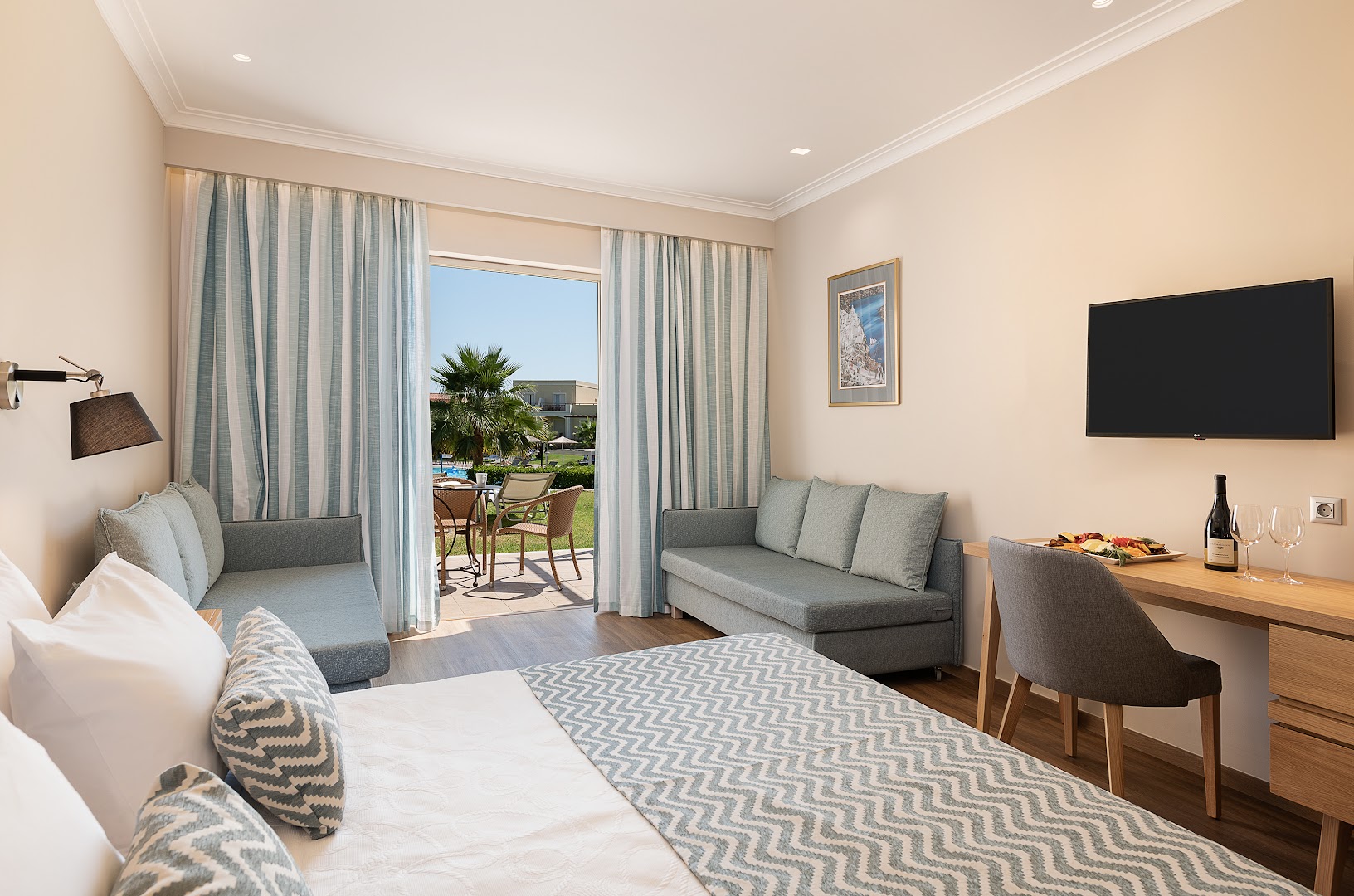 Moderns Pilot Beach Resort ģimenes numurs ar gaišu interjeru, divām dīvāngultām un terasi, no kuras paveras skats uz dārzu