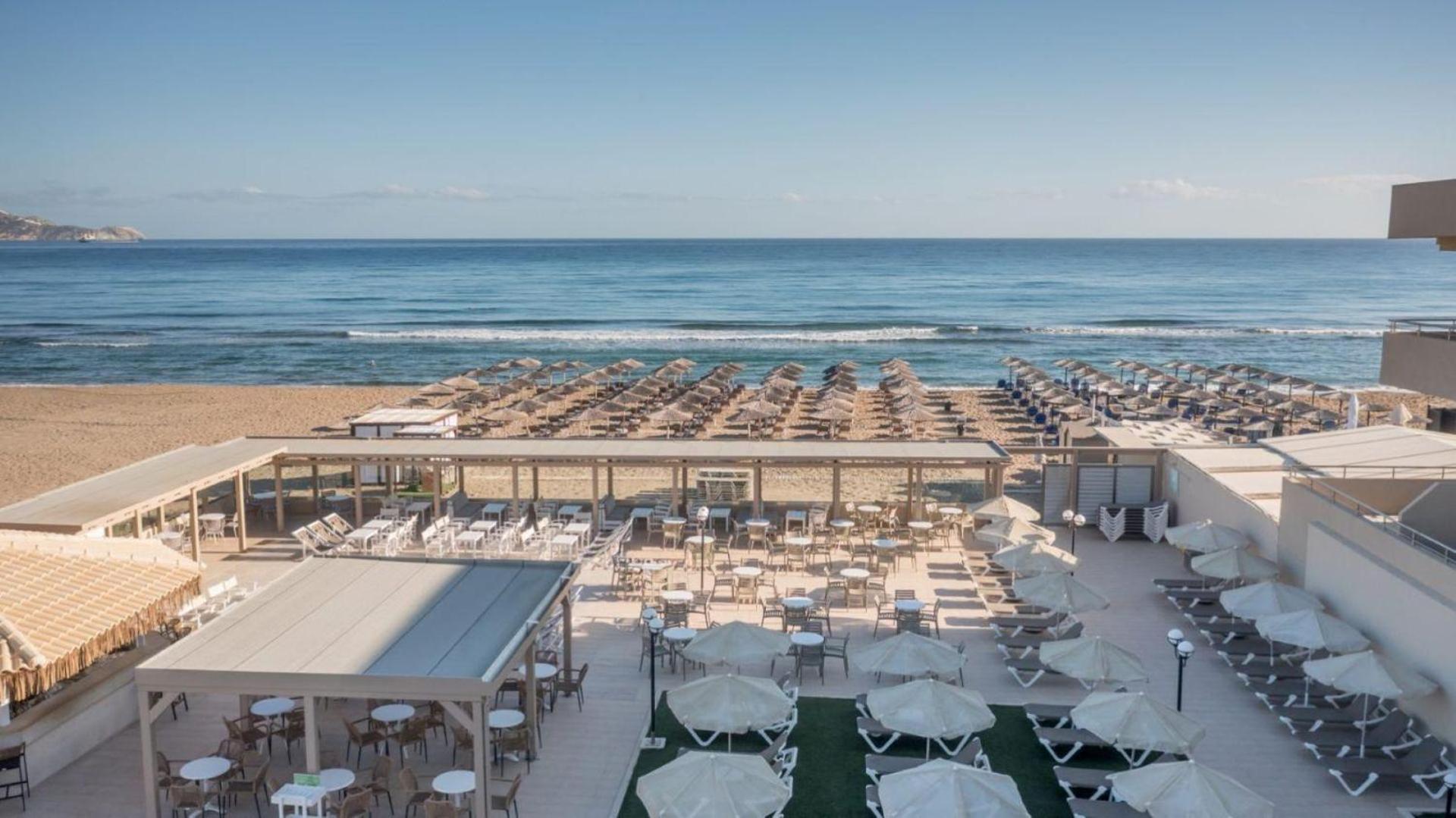 Panorāmas skats uz Zeus Hotels Neptuno Beach pludmales zonu, saulessargiem un āra kafejnīcu Amudarā, Krētā