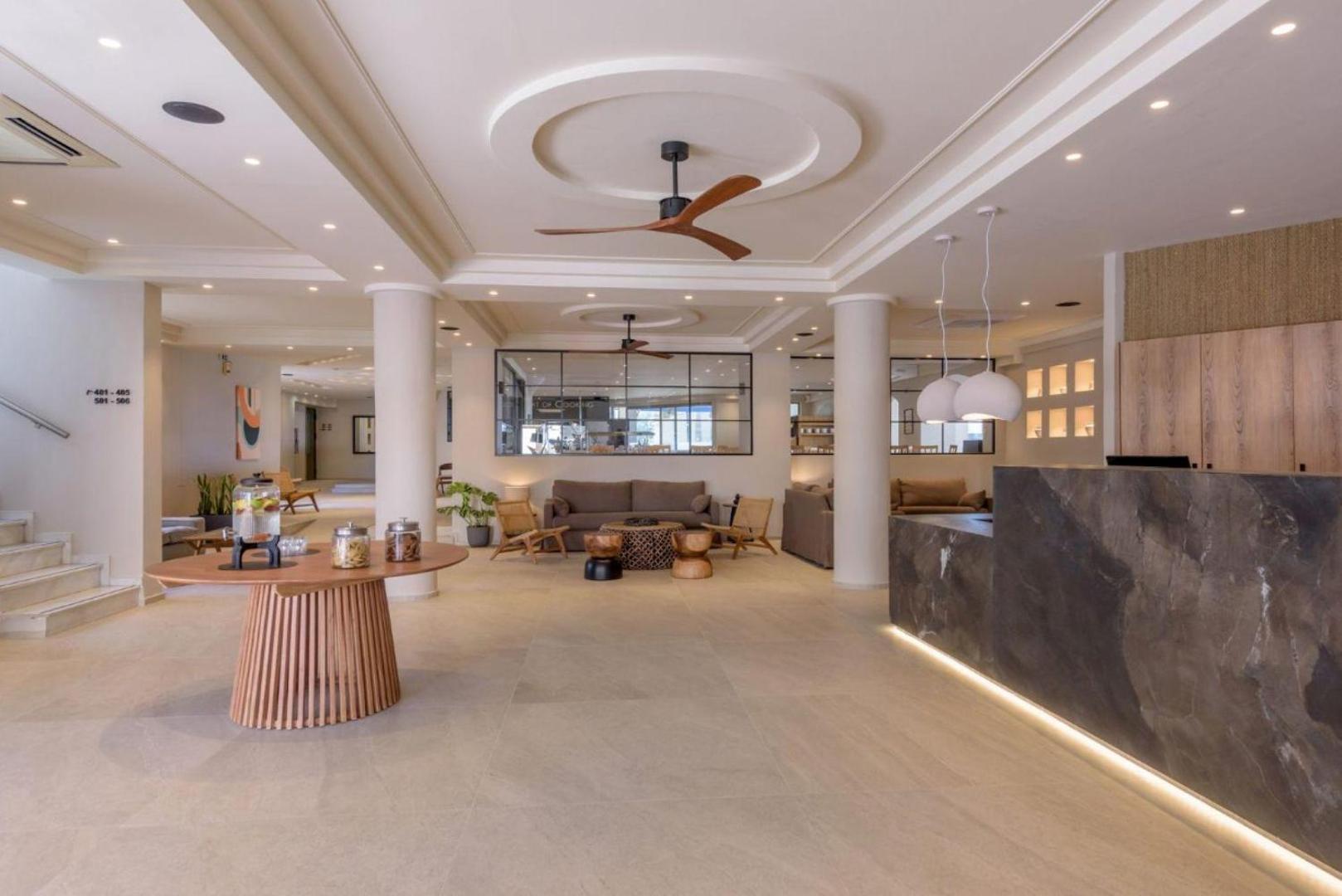 Zeus Hotels Neptuno Beach modernā recepcija un lobby zona ar gaišu interjeru, dīvāniem un koka dizaina elementiem