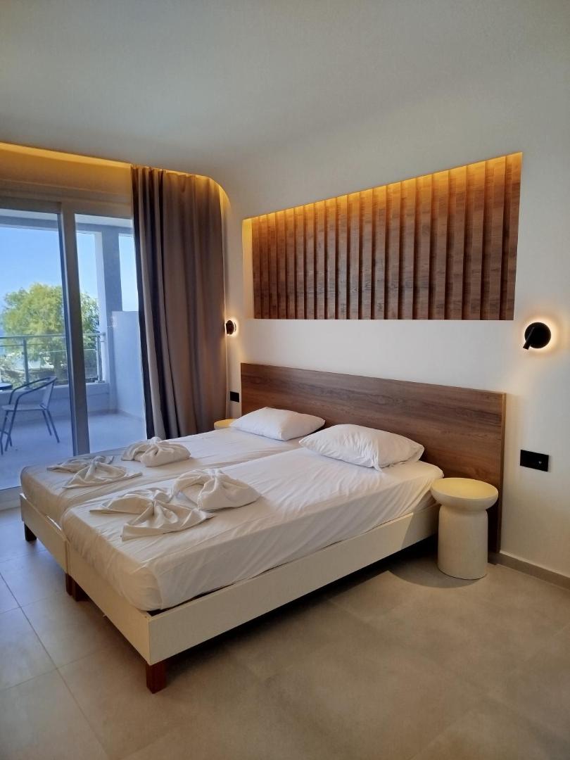 Neon Hotel gaišs numurs ar koka galvgali, dekoratīvu sienas paneli un izeju uz balkonu Stalidas kūrortā