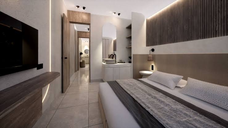 Neon Hotel numura interjers ar skatu uz vannas istabas zonu, koka sienas paneļiem un plašu divguļamo gultu