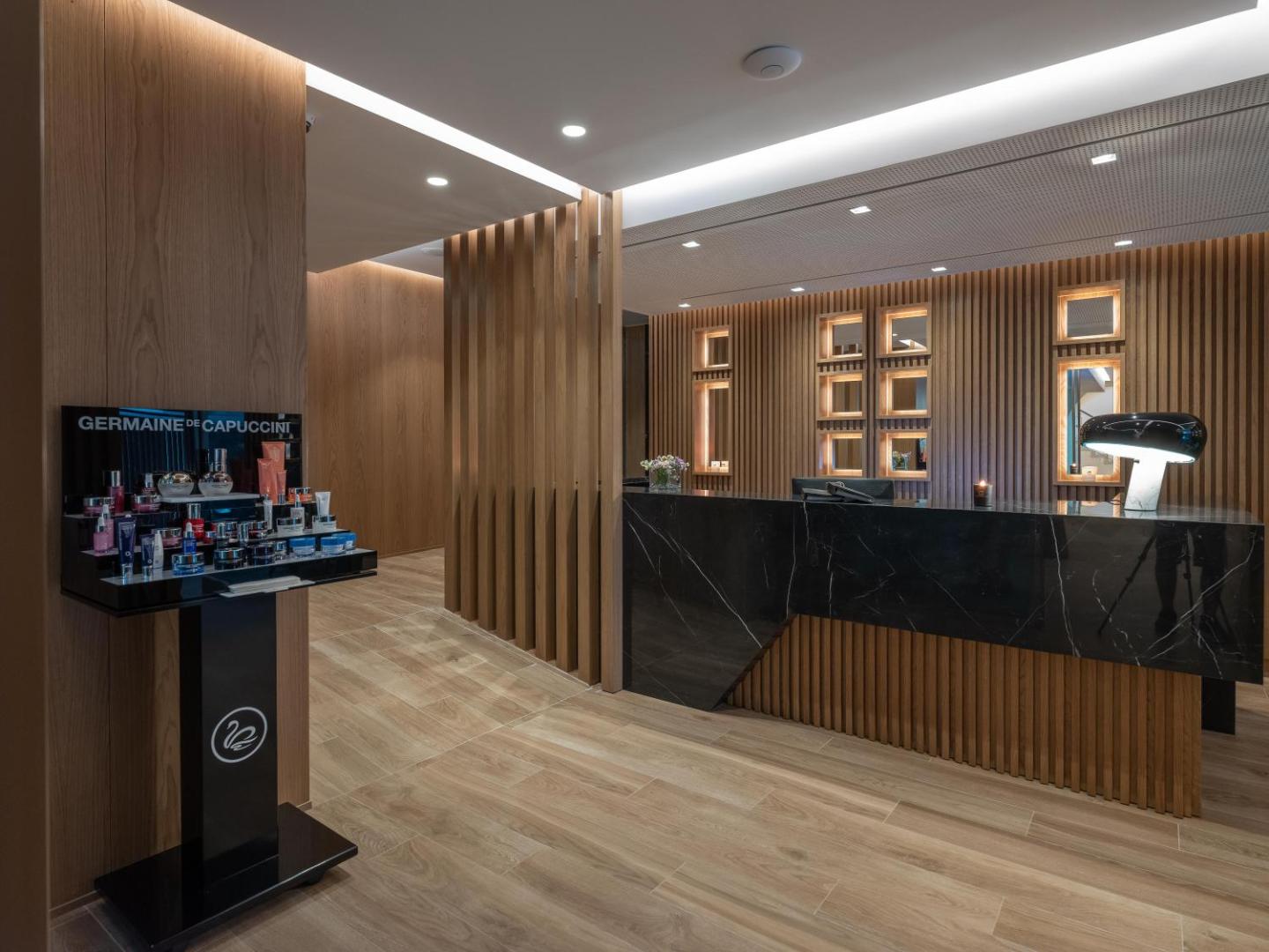 Nana Golden Beach viesnīcas spa centra recepcija ar tumša marmora leti, koka apdari un Germaine de Capuccini kosmētikas stendu