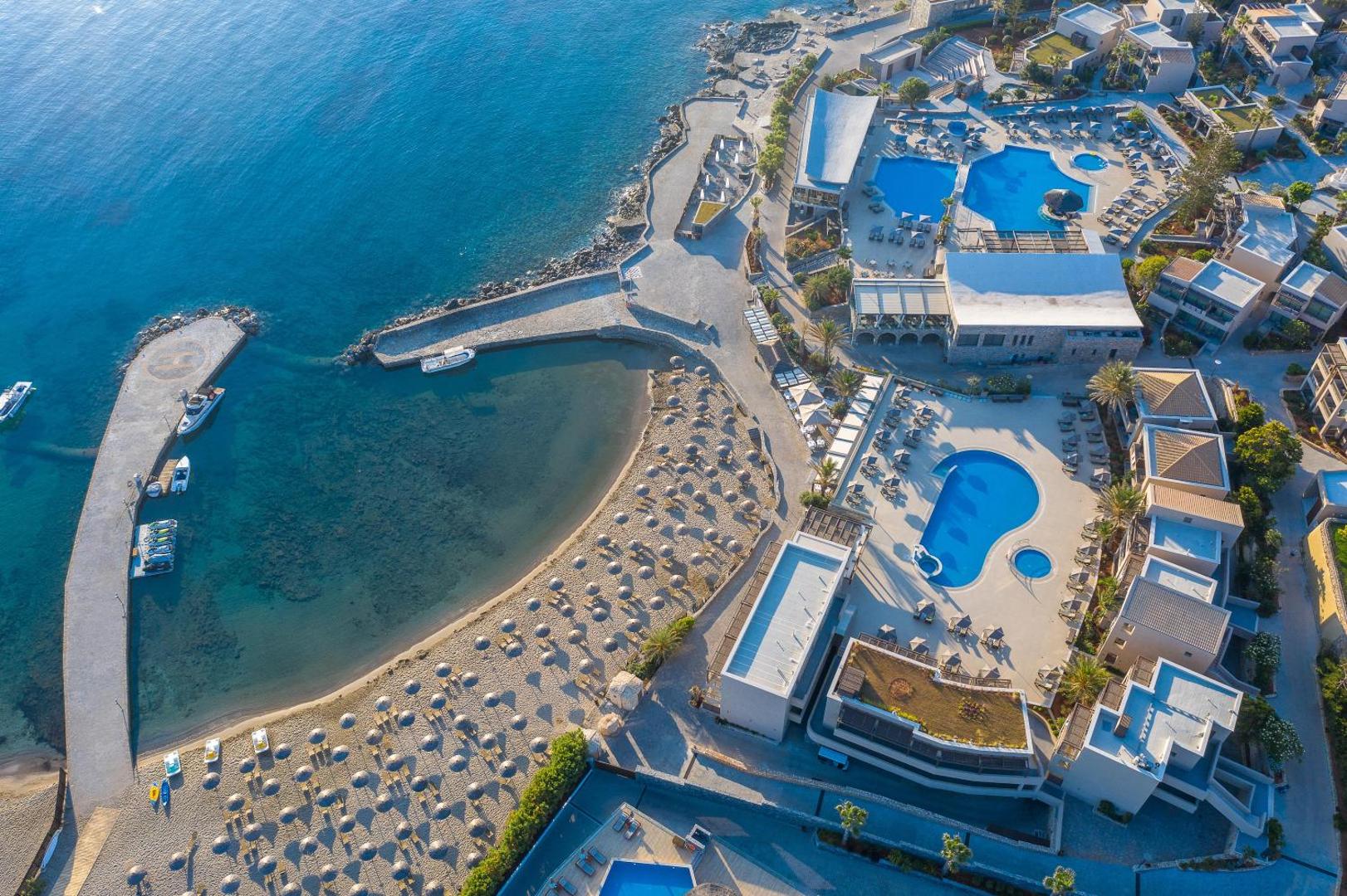 Nana Golden Beach viesnīcas skats no augšas uz privāto līci, smilšu pludmali ar saulessargiem un āra baseiniem Hersonisā, Krētā