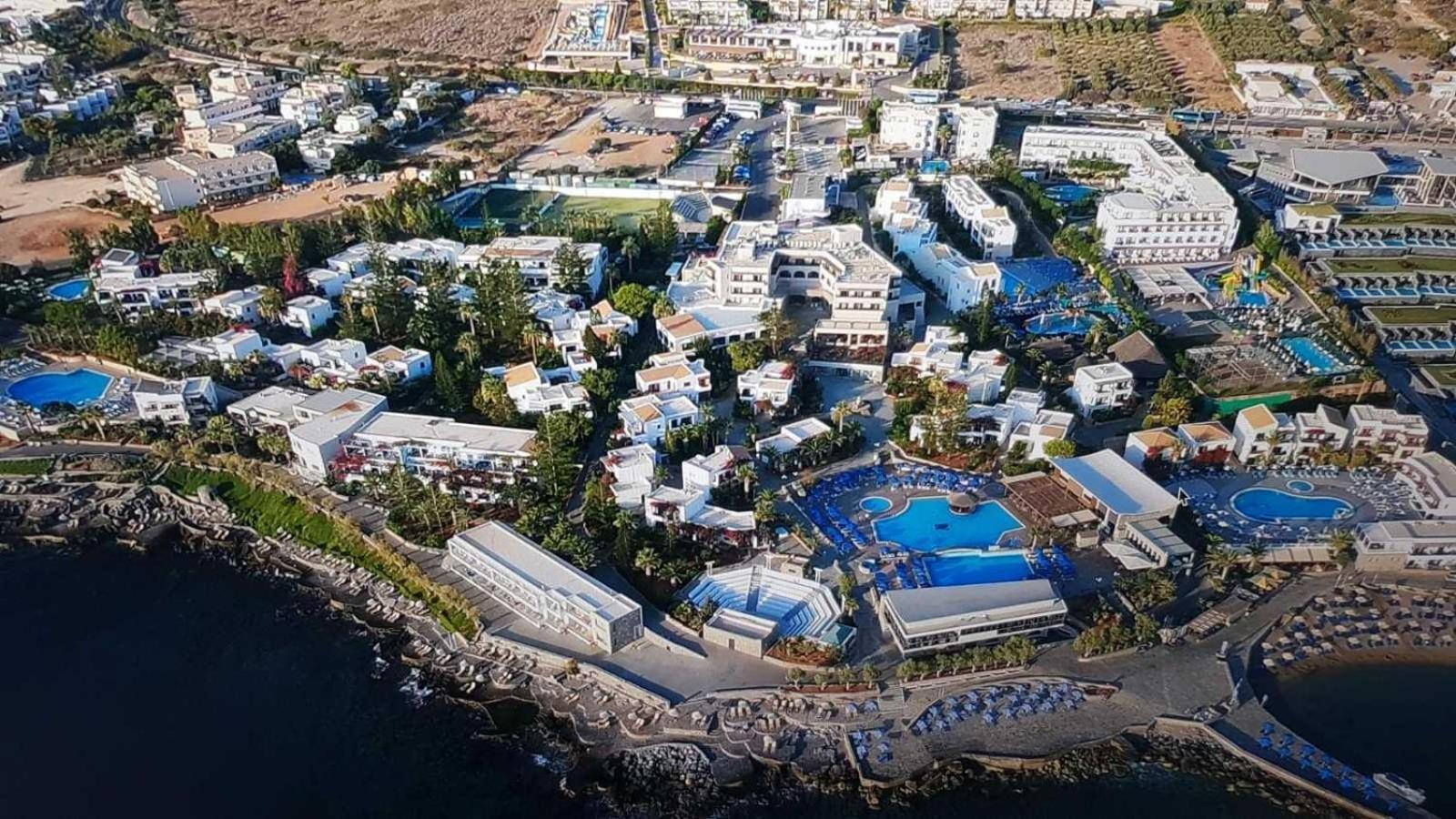 Nana Golden Beach kūrorta plašā teritorija no putna lidojuma ar daudzstāvu korpusiem, baseiniem un apstādījumiem Krētas piekrastē