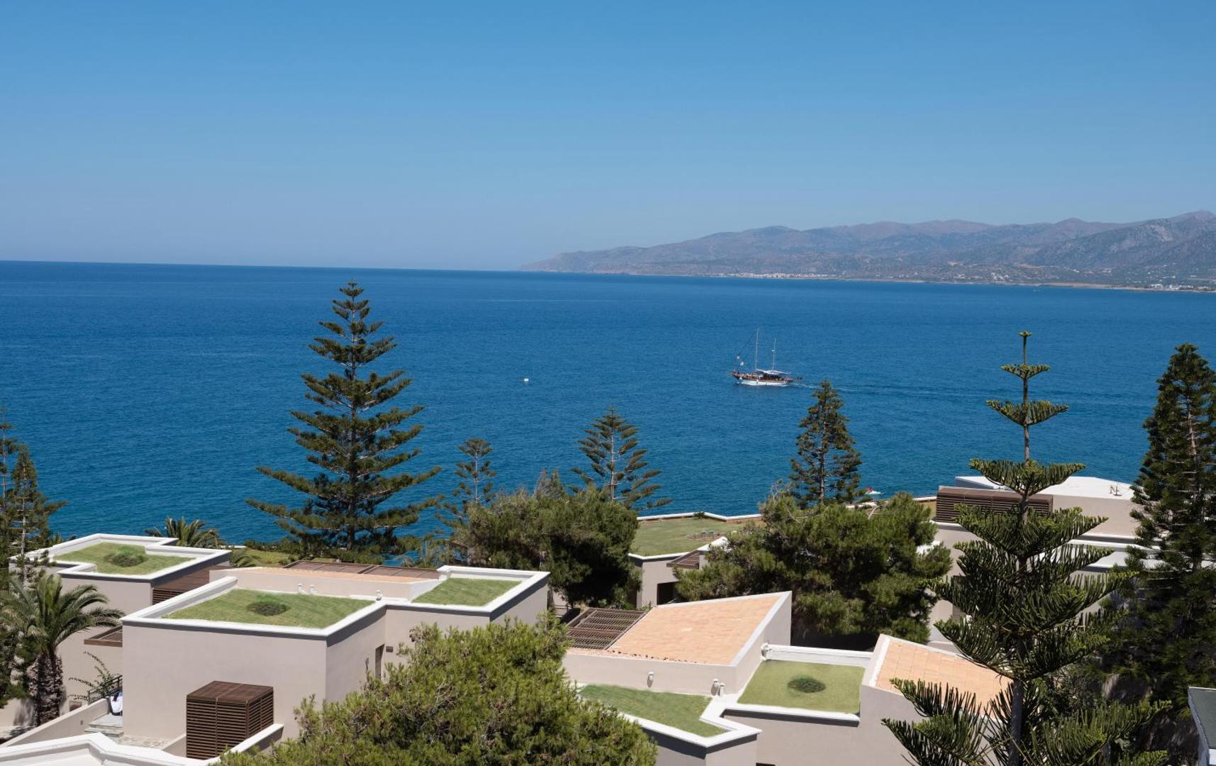 Skats no Nana Golden Beach uz zilo jūru un piekrastes bungalo ar zaļajiem jumtiem priežu ielokā