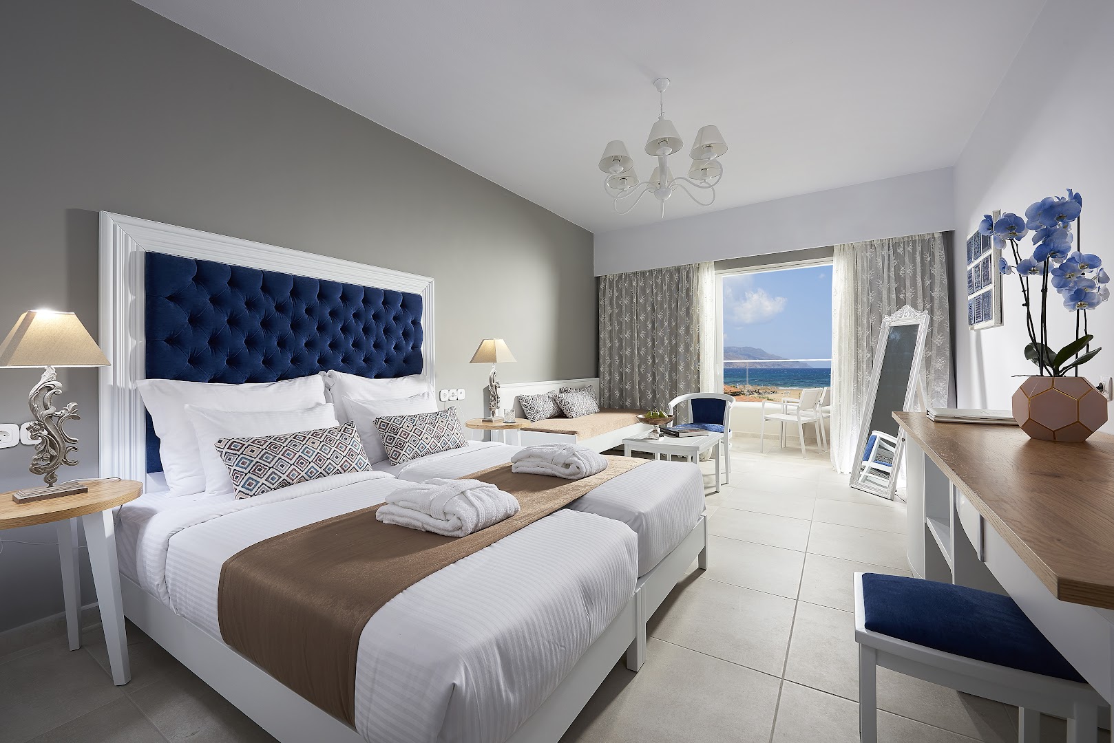 Mythos Palace Resort & Spa luksusa numurs ar tumši zilu galvgali, koka mēbelēm un skatu uz jūru no balkona