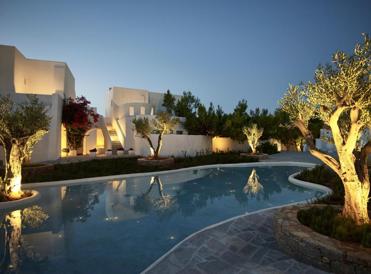 Knossos Beach Bungalows Resort vakara apgaismojums pie baseina un olīvkokiem, tradicionālā grieķu arhitektūra baltos toņos Krētas piekrastē