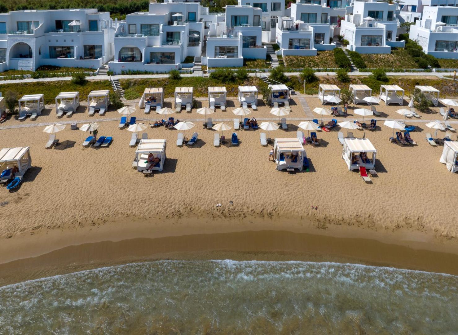 Knossos Beach Bungalows Resort balti bungalo pie pašas pludmales ar saulessargiem un ērtām gultām atpūtai smiltīs Krētas piekrastē