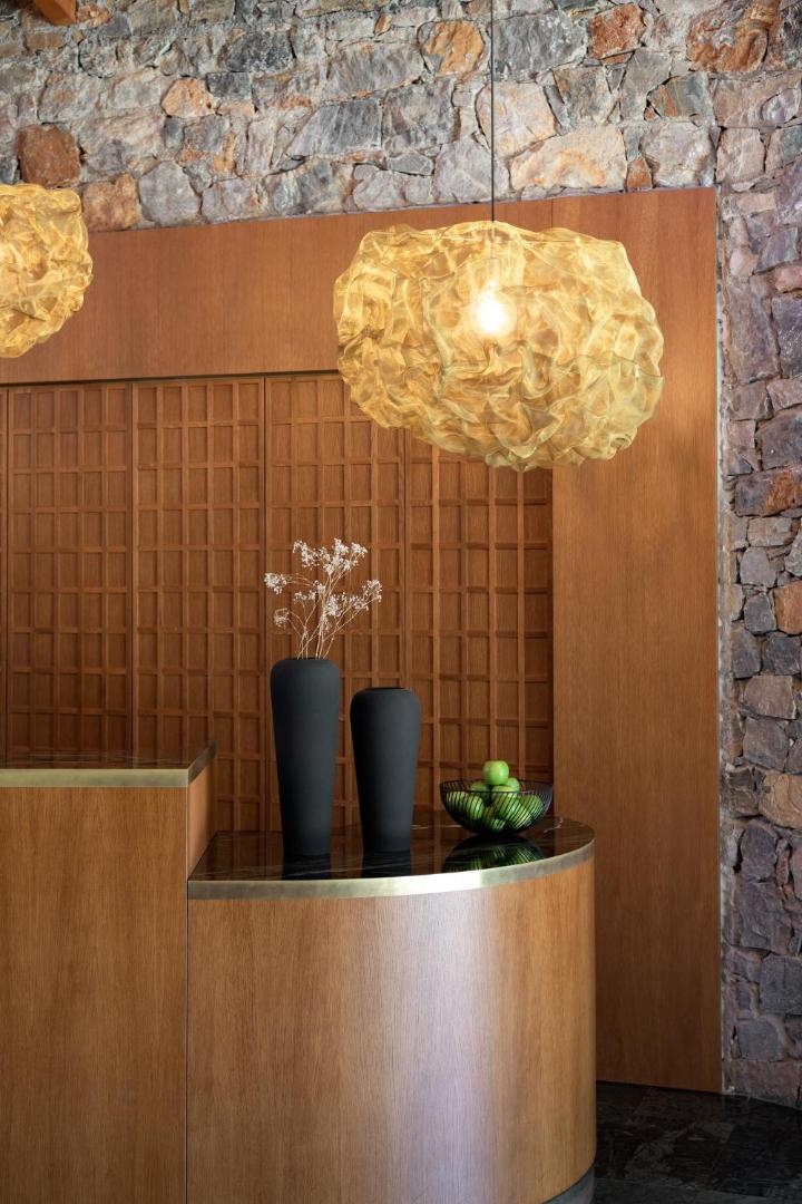 Ikaros Beach Resort & Spa dizaina detaļas — koka apdare, akmens siena un stilīgi gaismas ķermeņi viesnīcas interjerā