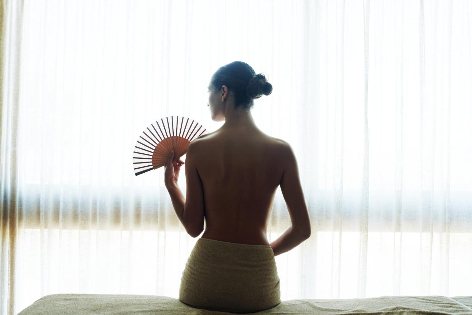Ikaros Beach Resort & Spa spa centra apmeklētāja ar vēdekli pie loga Krētā — relaksējoša atmosfēra un profesionālas procedūras