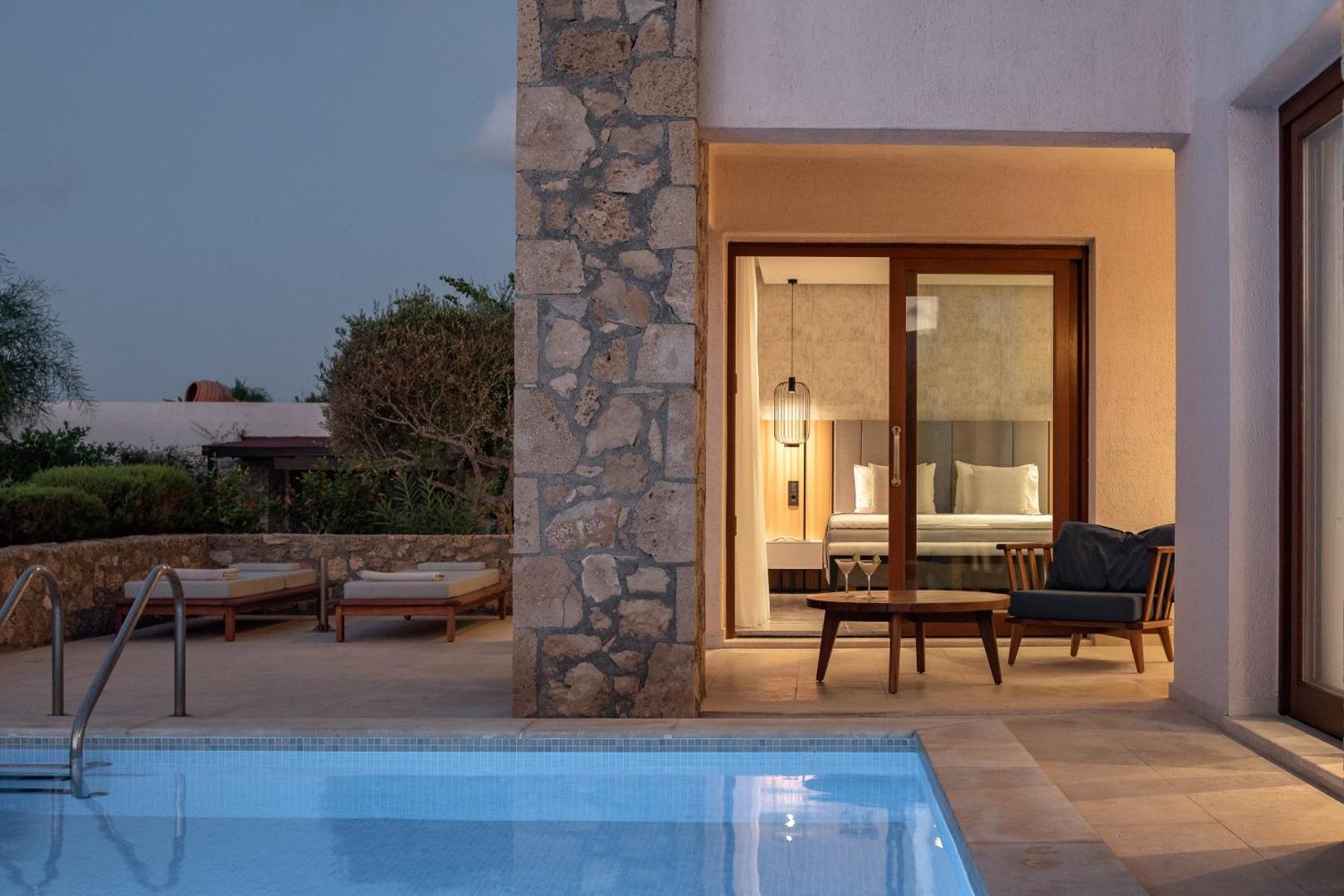 Ikaros Beach Resort & Spa numurs ar izeju uz privātu baseinu un terasi vakara apgaismojumā Krētā