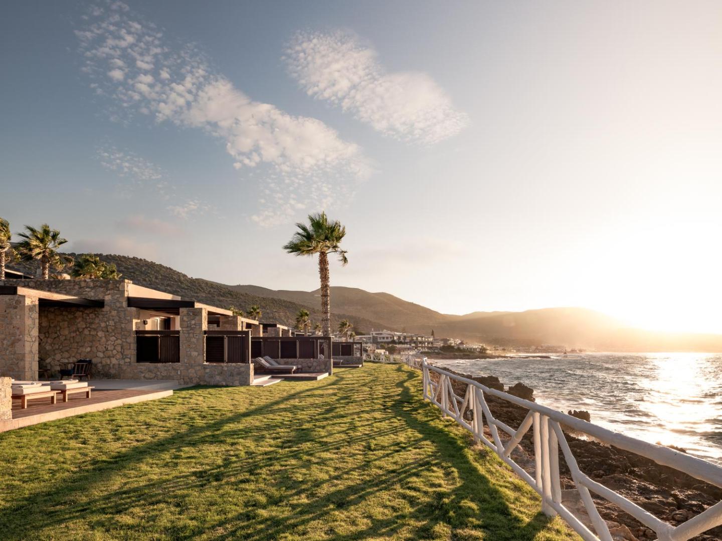 Ikaros Beach Resort & Spa numuru terases piekrastē saulrieta laikā ar skatu uz jūru un kalniem Krētā
