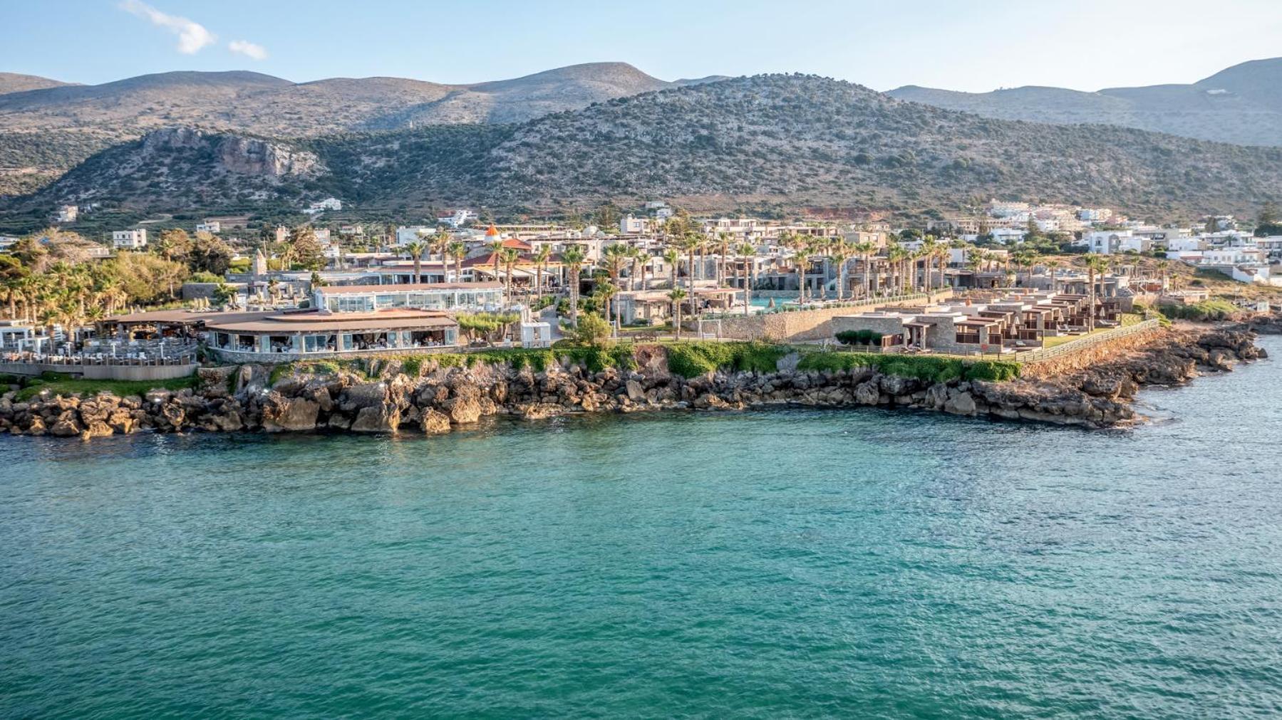 Ikaros Beach Resort & Spa viesnīcas komplekss tieši pie Vidusjūras krasta ar restorānu terasēm un akmeņainu pludmali