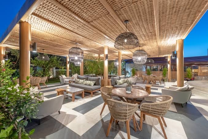 Ikaros Beach Resort & Spa āra atpūtas zona ar pītiem krēsliem un stilīgiem gaismekļiem zem koka nojumes