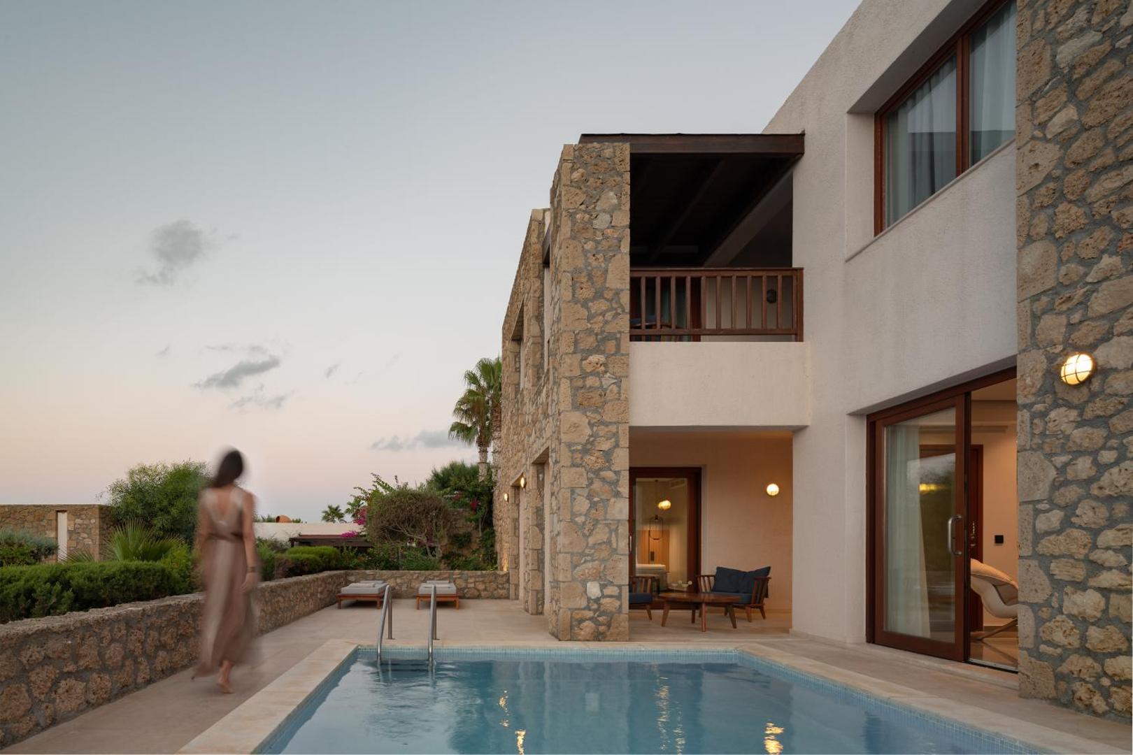 Ikaros Beach Resort & Spa divstāvu numurs ar akmens apdari, privātu baseinu un atpūtas zonu vakara apgaismojumā