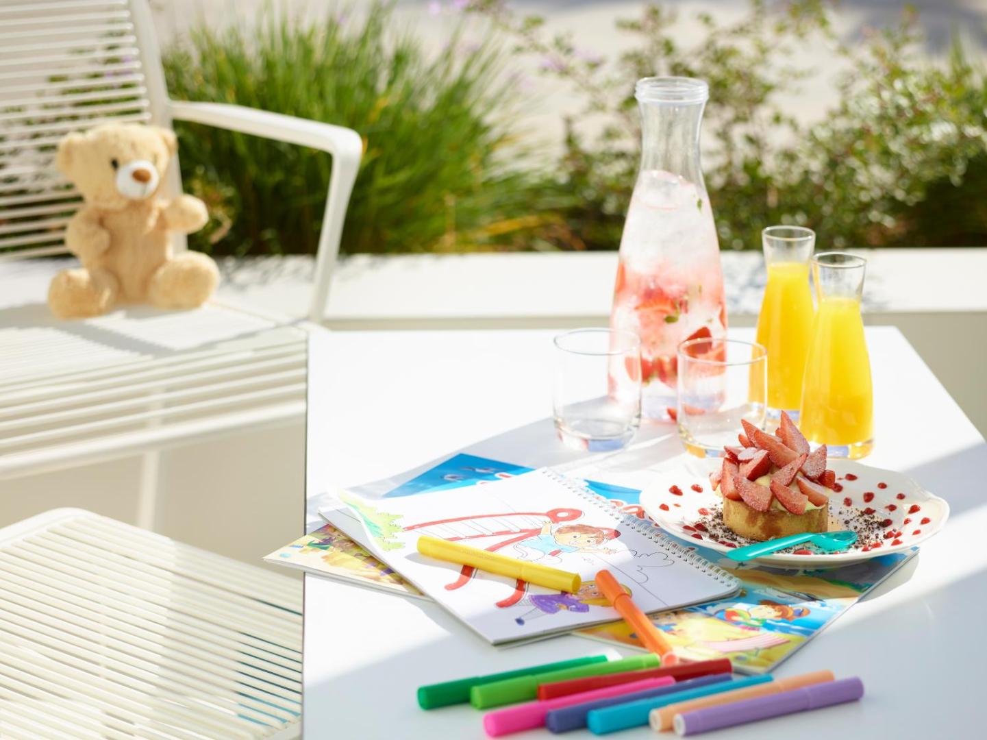 I-Resort Beach Hotel & Spa bērnu sagaidīšanas komplekts ar krāsojamo grāmatu, flomāsteriem, zemeņu desertu un atspirdzinošiem dzērieniem uz galda