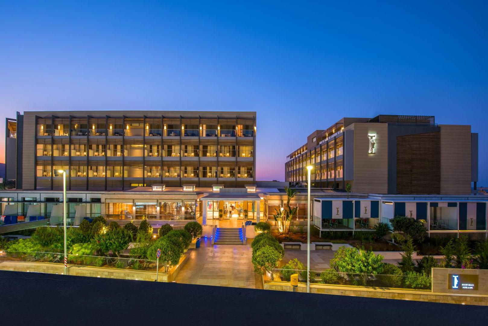 I-Resort Beach Hotel & Spa kopskats krēslas stundā — izgaismota pieczvaigžņu viesnīcas ēka ar dārzu un terasēm Stalidas kūrortā