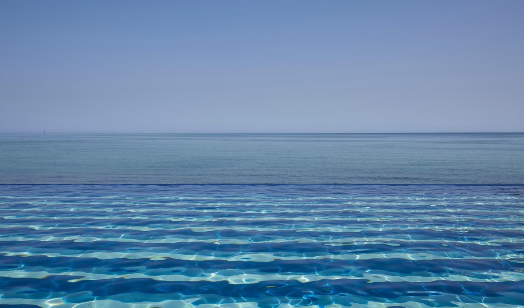 I-Resort Beach Hotel & Spa bezgalības baseins ar skatu uz horizontu un zilo Vidusjūru saulainā dienā Krētas piekrastē