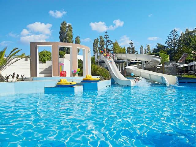 Grecotel Creta Palace āra baseins ar ūdens slidkalniņiem un bērnu atpūtas zonu — plaša teritorija ģimenes atpūtai pie jūras