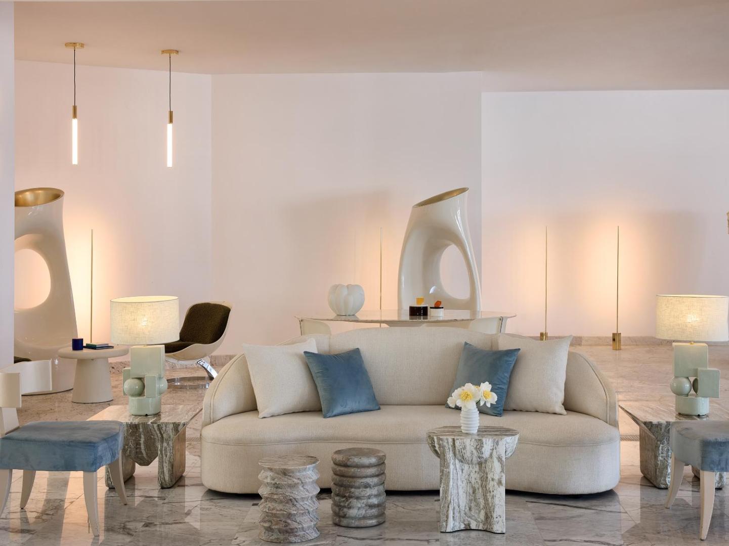 Grecotel Creta Palace Resort modernais lobby interjers ar gaišām mēbelēm, dizaina elementiem un marmora grīdu