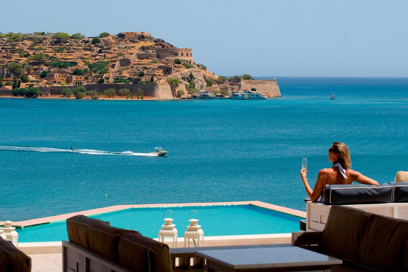 Domes of Elounda Autograph Collection skats no terases uz Spinalongas salu un tirkīzzilo jūru ar atpūtas zonu un baseinu