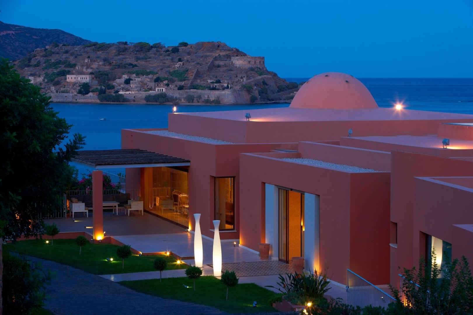 Domes of Elounda viesnīcas arhitektūra vakarā ar skatu uz Spinalongas salu un Mirabello līci Krētas piekrastē