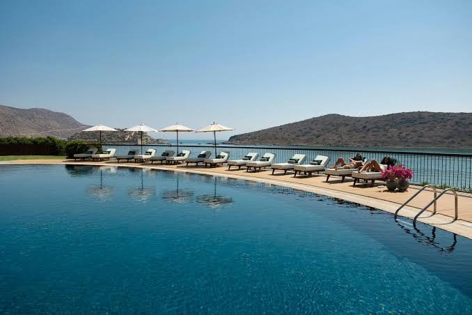 Domes of Elounda Autograph Collection bezmalas baseins ar saulessargiem un sauļošanās krēsliem pie pašas jūras krasta līnijas