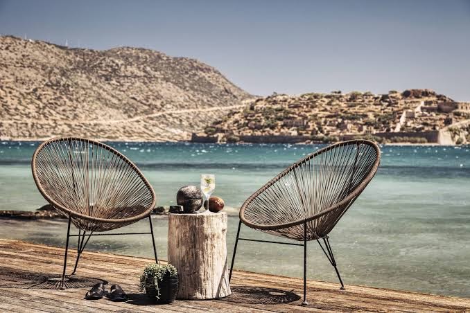 Domes of Elounda Autograph Collection atpūtas zona pie jūras ar dizaina krēsliem, skatu uz Spinalongas salu un dzidru ūdeni Krētā