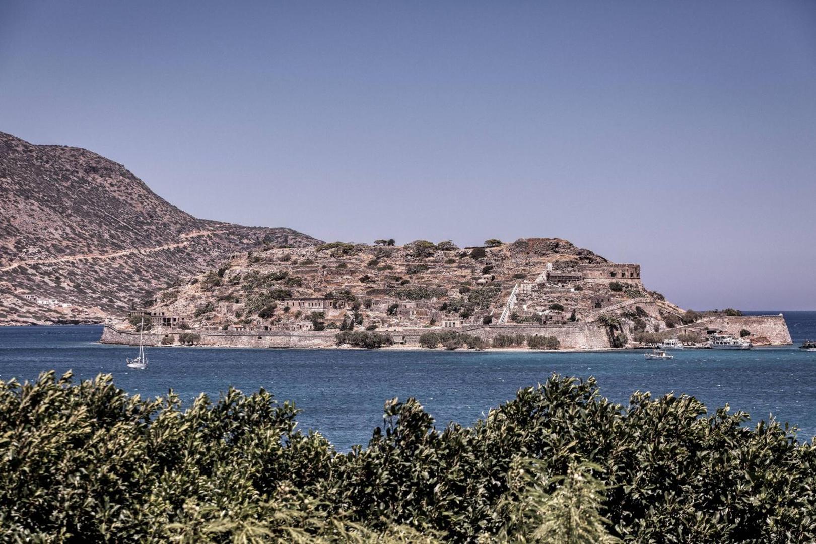 Skats no Domes of Elounda viesnīcas uz vēsturisko Spinalongas salu un cietoksni pāri zilajiem Mirabello līča ūdeņiem Krētā