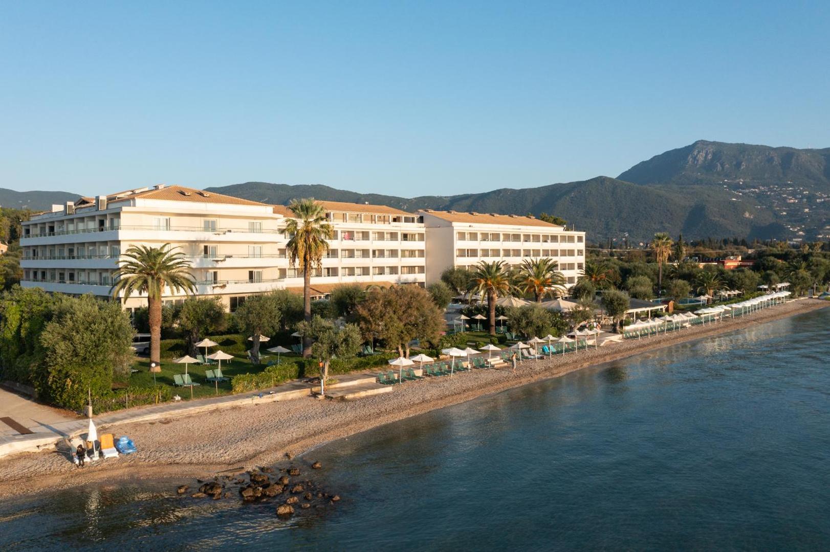 Elea Beach Hotel skats no putna lidojuma uz viesnīcas ēku, oļu pludmali un Jonijas jūru Korfu salā, Grieķijā