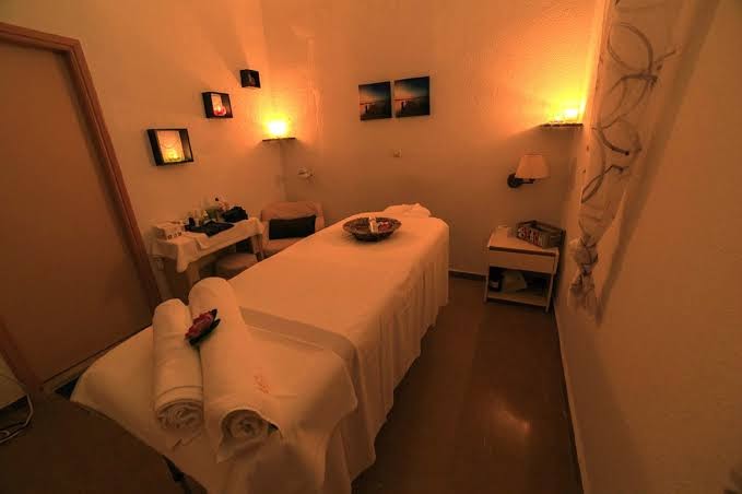 Elea Beach Hotel spa procedūru telpa ar masāžas galdu, siltu apgaismojumu, svecēm un sagatavotiem dvieļiem relaksācijai