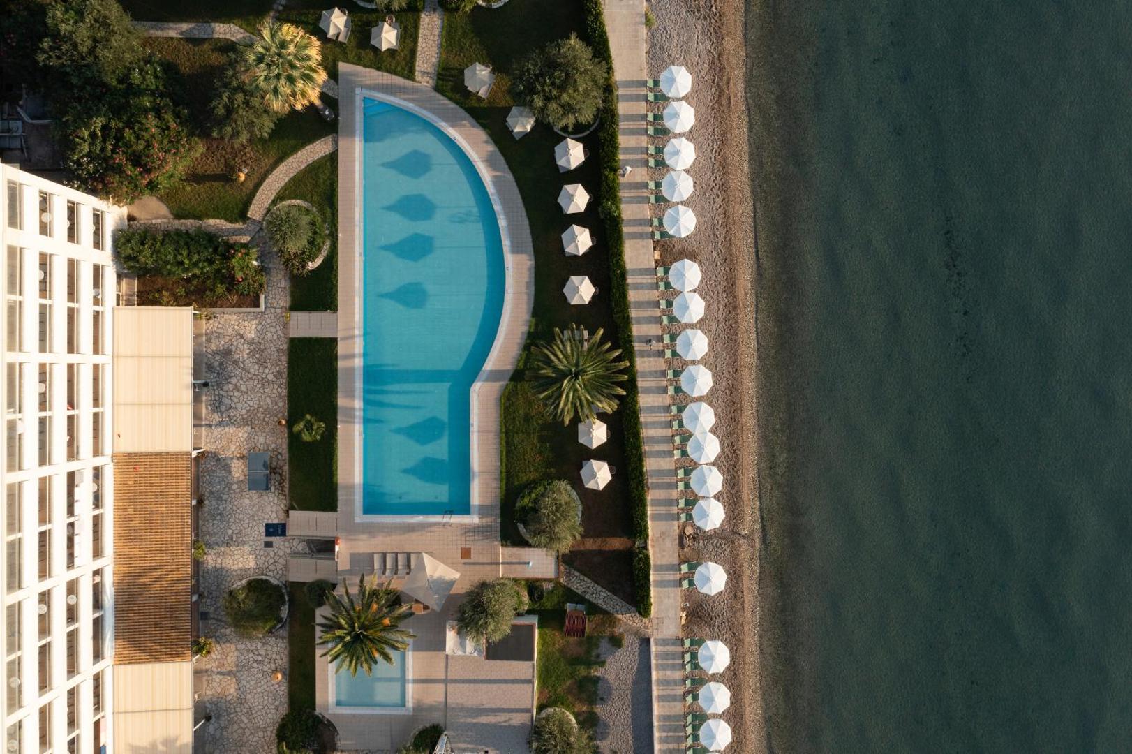 Elea Beach Hotel skats no putna lidojuma uz zilo baseinu, saulessargiem pludmalē un dzidro jūras ūdeni