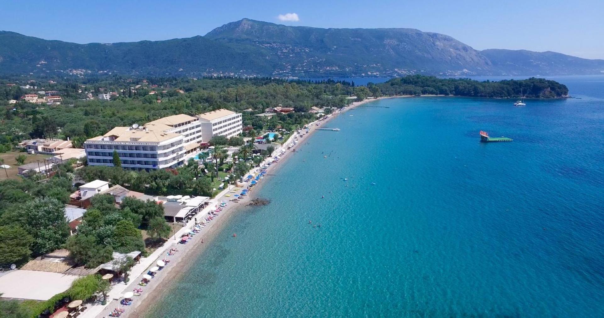 Elea Beach Hotel plašais skats uz tirkīzzilo jūru, garo pludmali un zaļajiem kalniem Korfu piekrastē