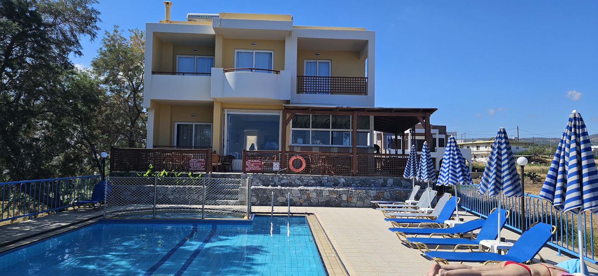 Danaos Beach Apartments viesnīcas ēka ar balkoniem un baseinu priekšplānā saulainā dienā Krētā