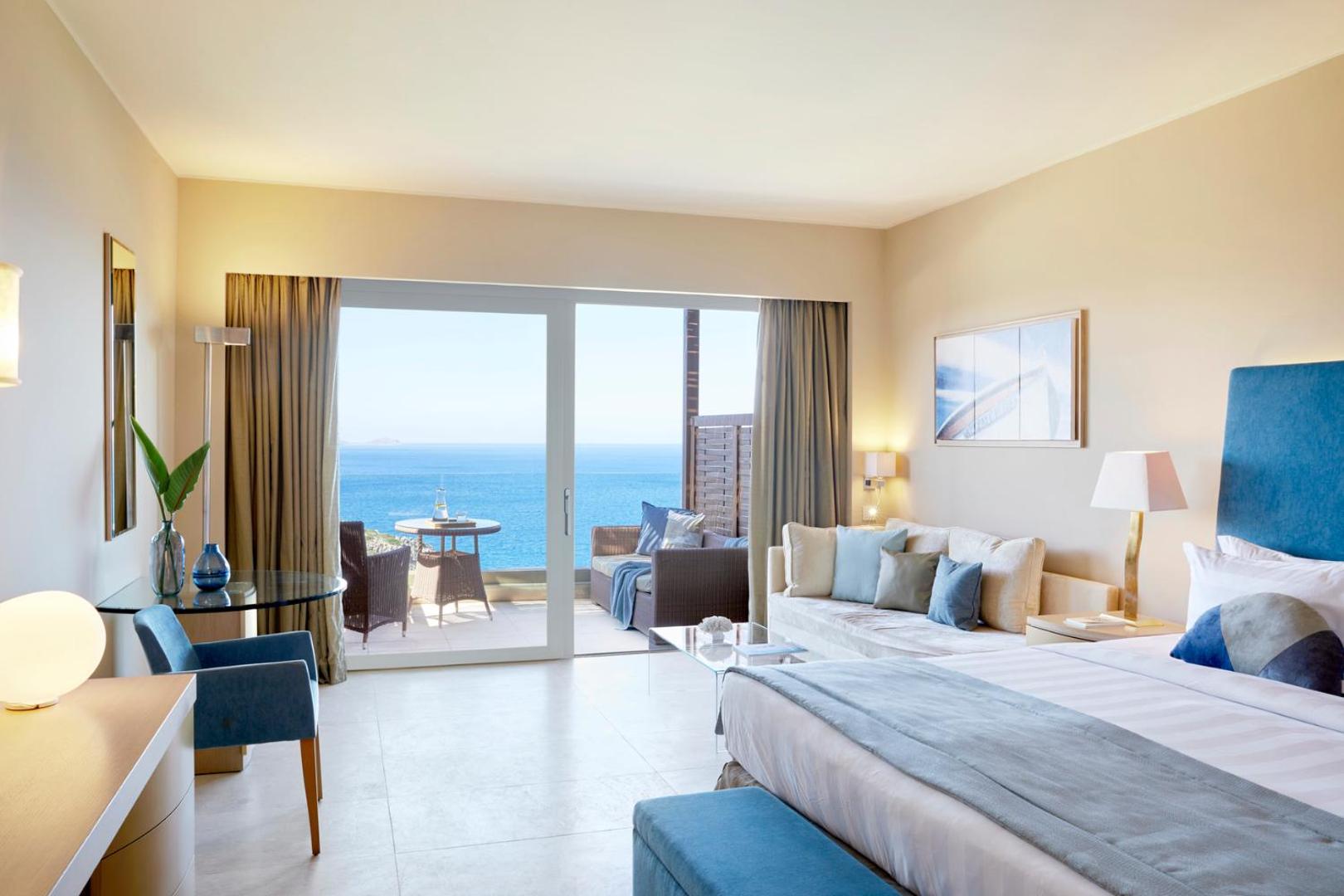 Daios Cove Luxury Resort gaišs numurs ar skatu uz jūru, atpūtas zonu un plašu terasi piekrastē