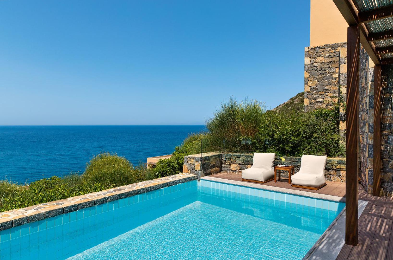 Daios Cove Luxury Resort privātais baseins ar atpūtas krēsliem uz terases un panorāmas skatu uz zilo jūru