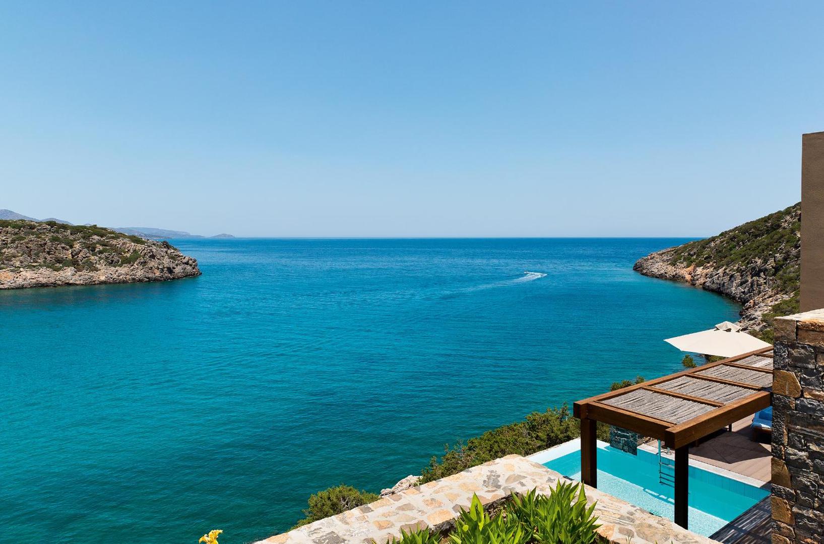 Daios Cove Luxury Resort skats no numura terases uz tirkīzzilo līci Krētā ar privātu baseinu un akmens mūriem
