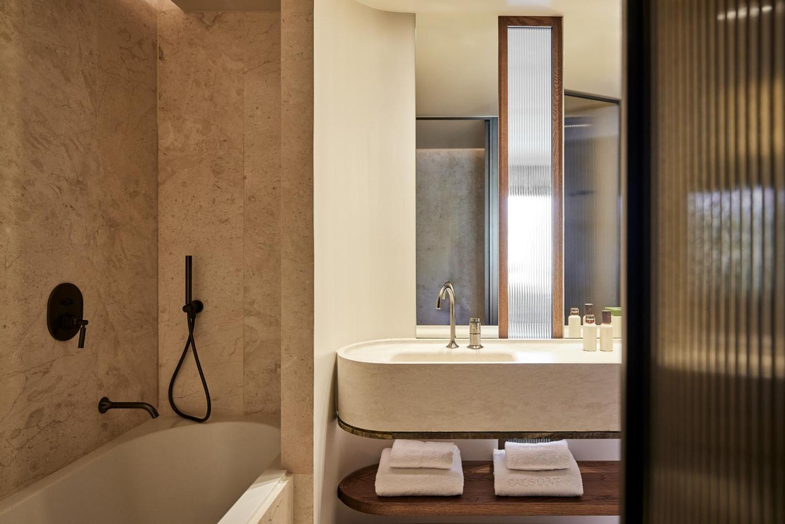 Daios Cove Luxury Resort numura vannas istaba ar marmora apdari, vannu un elegantu izlietni — gaišs un luksusa dizains