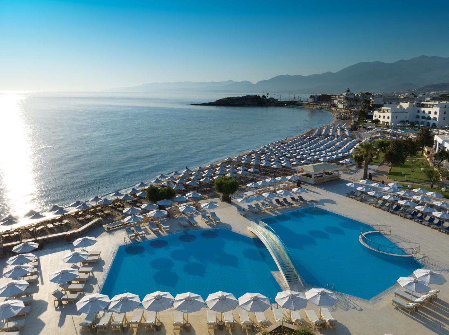 Creta Maris Resort panorāmas skats uz āra baseiniem, privāto pludmali un kalniem Hersonisā, Krētā saulrieta laikā