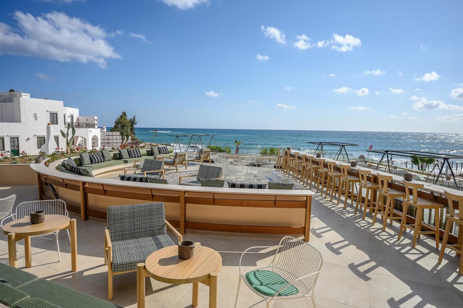 Plaša Creta Maris Resort atpūtas terase ar bāra krēsliem un dīvāniem tieši pie jūras krasta Hersonisā