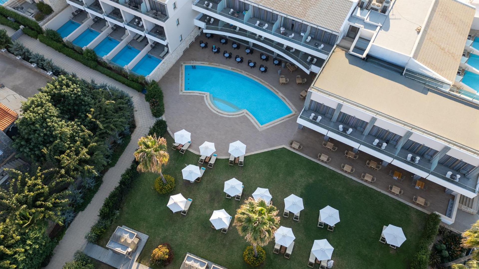 Castello Boutique Resort & Spa skats no augšas uz galveno baseinu, sauļošanās zonu ar saulessargiem un numuriem ar privātiem baseiniem Sisī, Krētā.