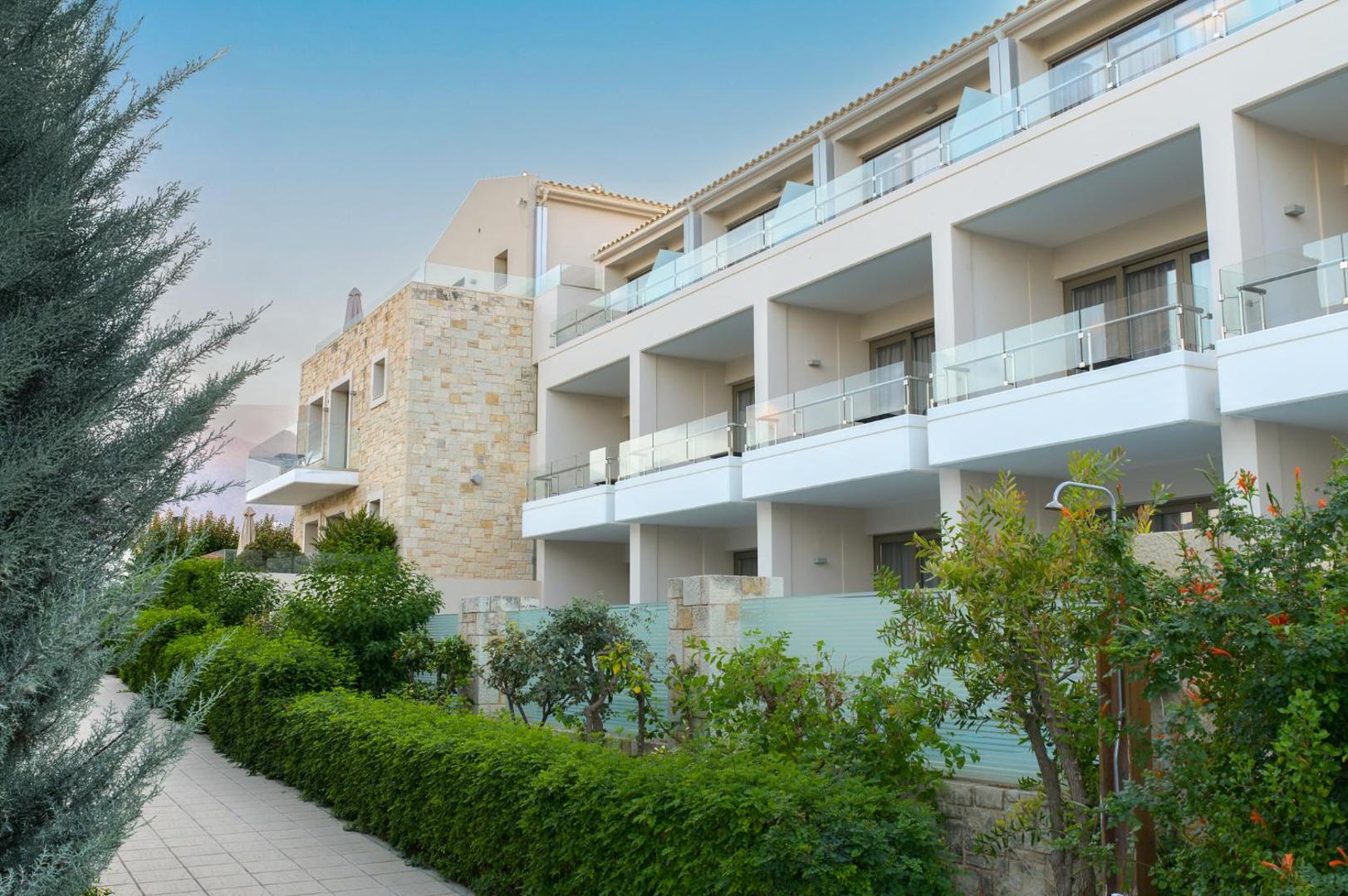 Castello Boutique Resort & Spa modernā arhitektūra ar gaišām fasādēm, stikla balkoniem un koptu dārzu ar zaļiem dzīvžogiem.