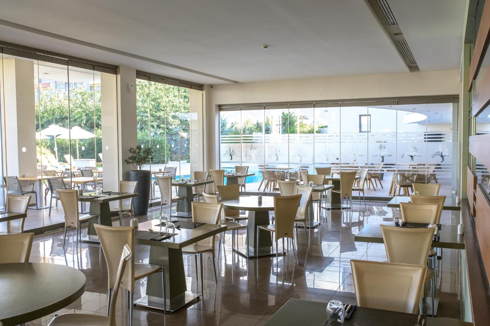 Castello Boutique Resort & Spa gaišā restorāna zāle ar modernām mēbelēm un skatu uz āra baseinu caur stikla sienām