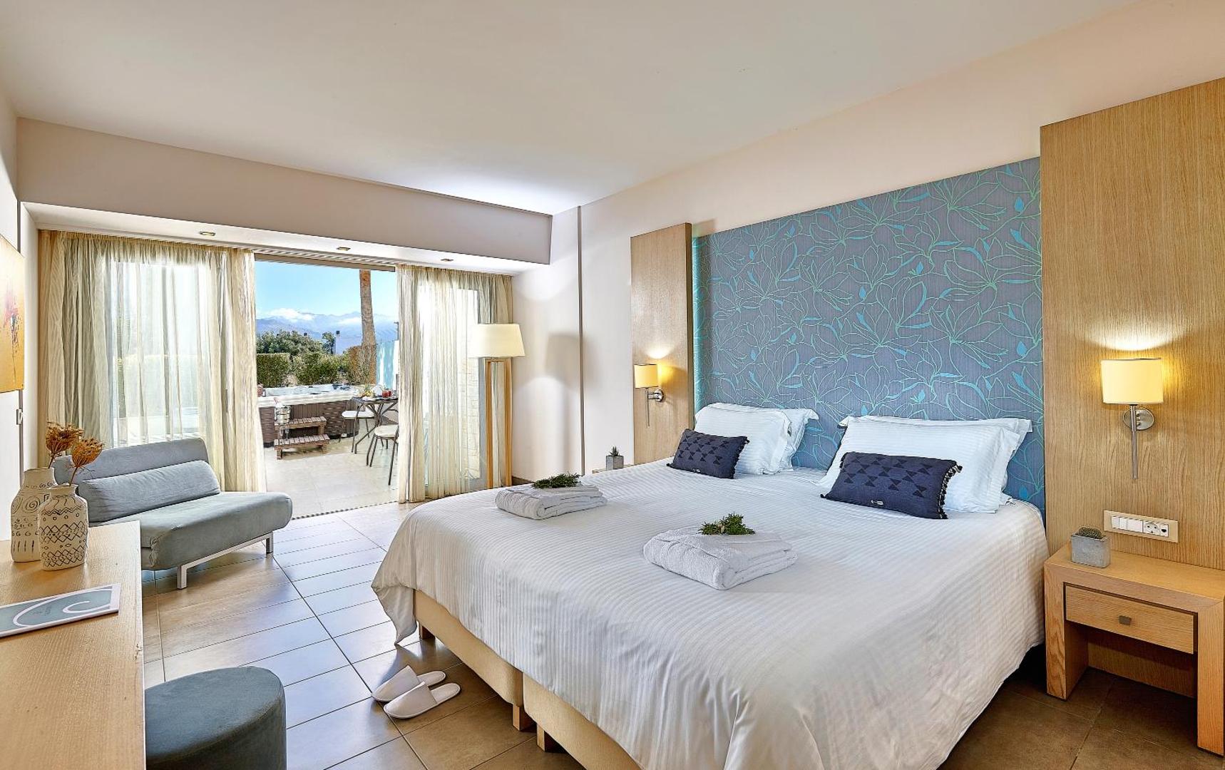Castello Boutique Resort & Spa gaišs viesnīcas numurs ar lielu gultu, zilu dekoratīvu sienu un izeju uz terasi