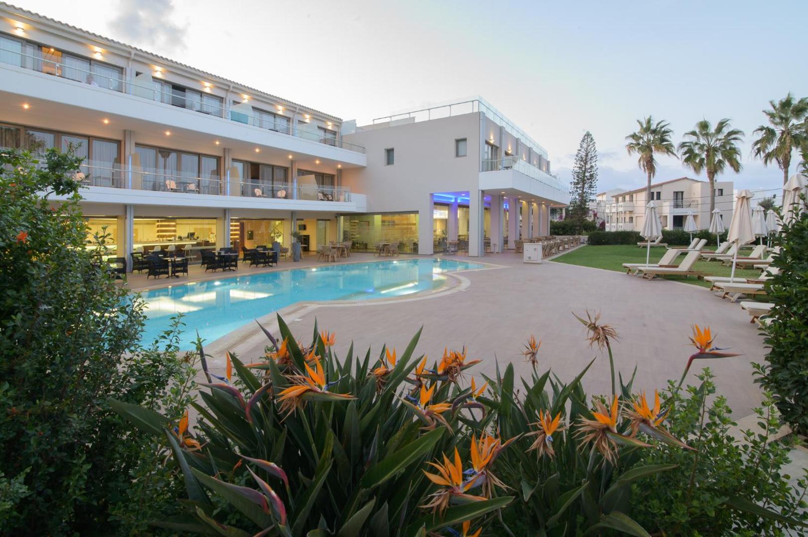 Castello Boutique Resort & Spa viesnīcas fasāde un baseins krēslas stundā — izgaismota terase, ziedoši augi un eleganta atpūtas zona