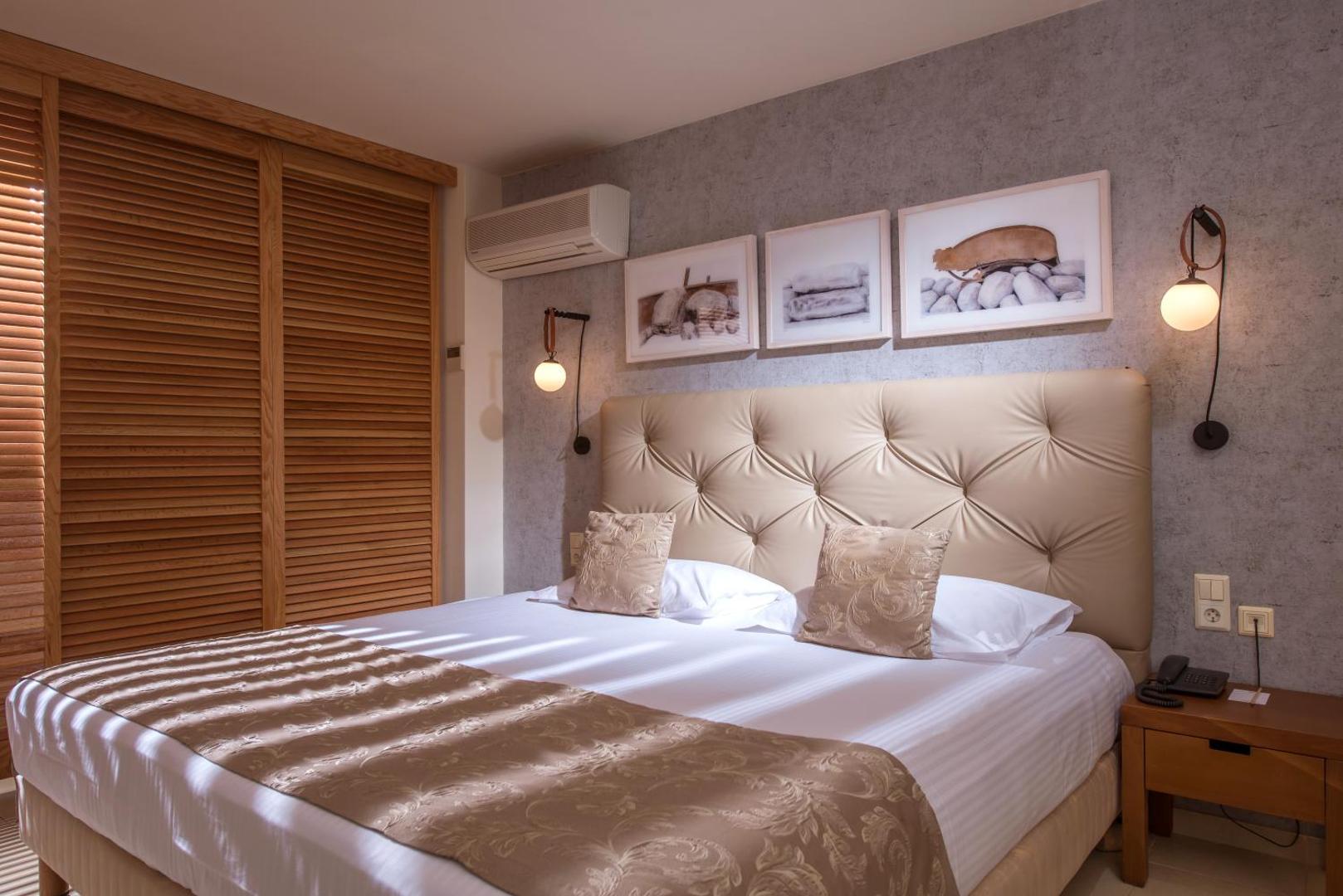 Bella Beach Hotel guļamistaba ar lielu gultu, dekoratīviem spilveniem un koka žalūzijām — mājīgs apgaismojums un kondicionieris komfortam