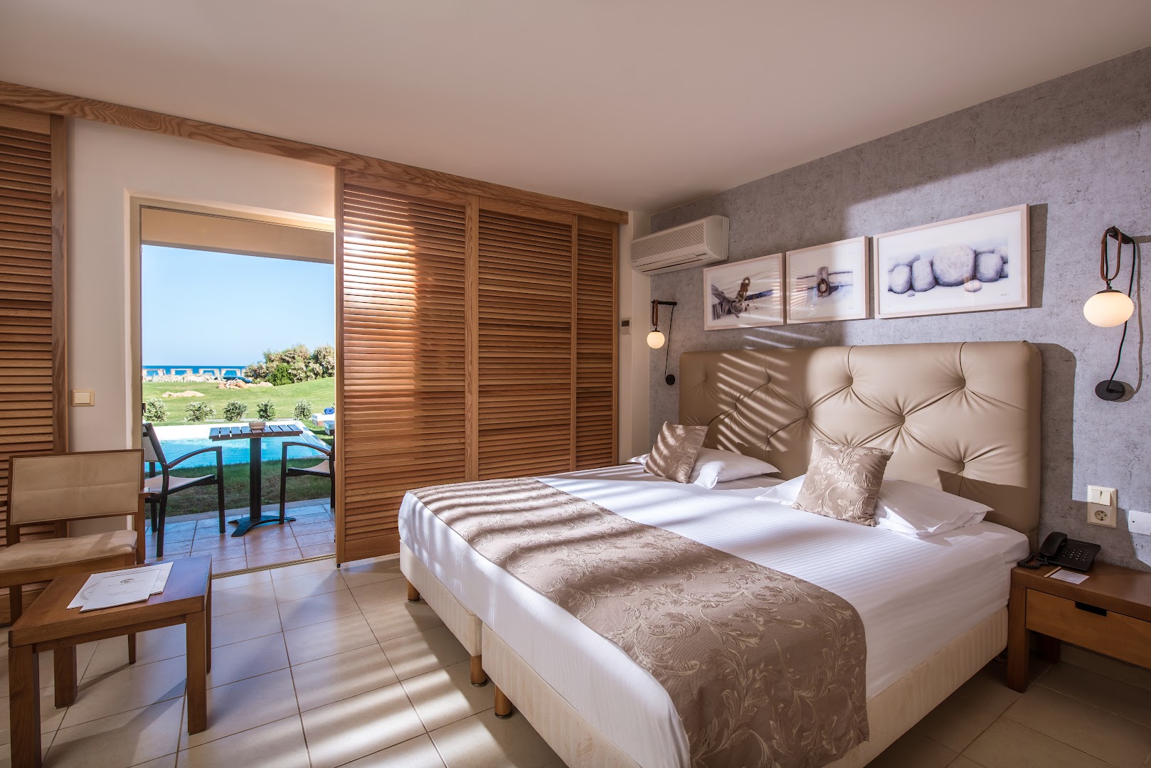 Gaišs Bella Beach Hotel numurs ar divguļamo gultu, koka žalūzijām un izeju uz terasi, no kuras paveras skats uz dārzu